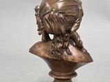 a bronze statue of a bird sitting on top of a bust