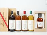 trois bouteilles de whisky dans un coffret en bois, avec un autre coffret en bois derrière elles