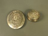 two antique brass buttons on a table with a green background