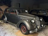 two old cars parked in a garage next to each other