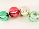 four shiny christmas ornaments are arranged in a row on a white surface