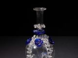 glass vase with blue flowers on it on a black surface