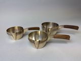 three metal measuring cups with wooden handles on a white surface