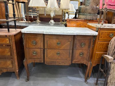 une commode au plateau en marbre sur laquelle sont posées deux lampes