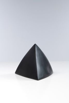un objet noir en forme de pyramide posé sur une surface blanche