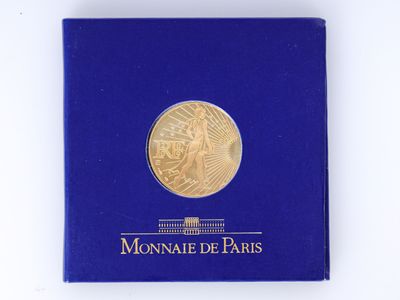 une boîte bleue contenant une pièce d'or, posée sur un fond blanc