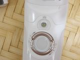 a white electric shaver sitting on the floor next to a book