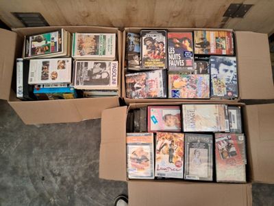 un grand nombre de DVD dans une boîte en carton posée sur le sol