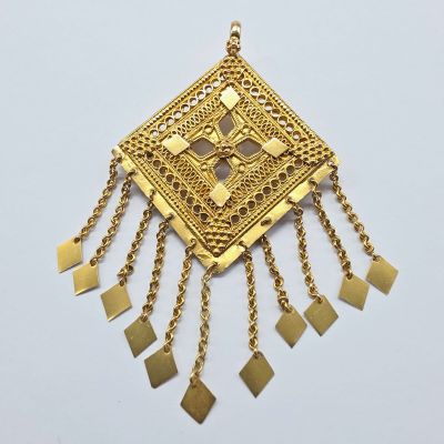 gros plan d'un collier en or sur une surface blanche