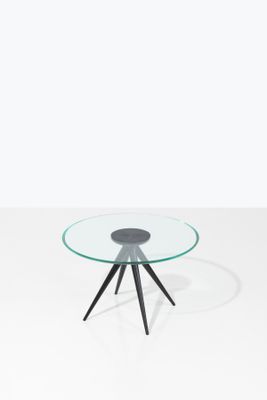 une table ronde en verre avec des pieds noirs et un plateau en verre