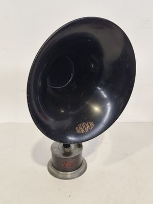un vieux gramophone noir posé sur un support, sur une surface blanche