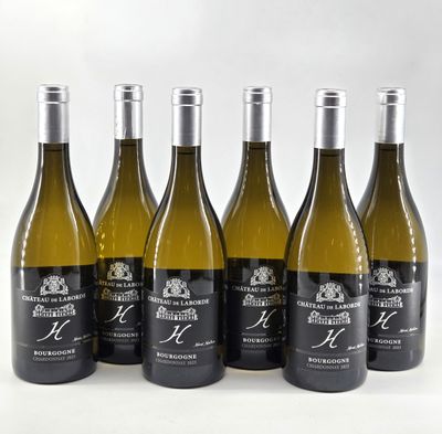 six bottles of wine are lined up in a row on a white surface