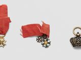 three medals and a crown on a white surface