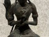 une statue de femme tenant un oiseau dans sa main