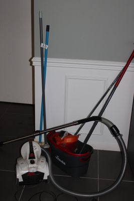 un aspirateur et une serpillière posés par terre près d'un mur