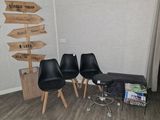 trois chaises noires dans une pièce où est accrochée une pancarte au mur