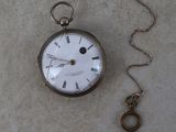 une montre de poche en argent à laquelle est attachée une clé