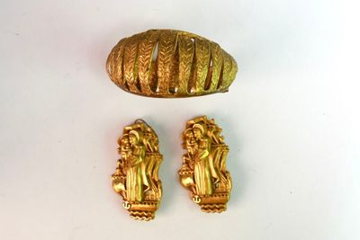 deux bijoux en or posés sur une surface blanche