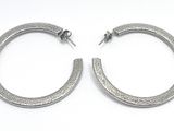une paire de boucles d'oreilles créoles en argent sur fond blanc