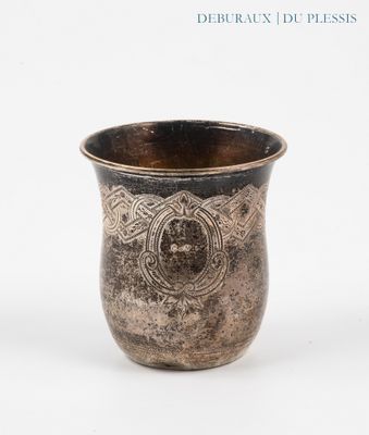 une tasse en argent posée sur une surface blanche