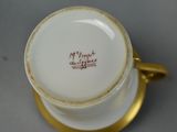 a white cup with a gold rim and a gold handle