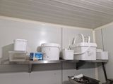 many buckets and containers sitting on a shelf in a kitchen