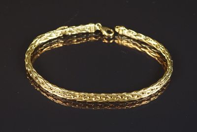 gros plan d'un bracelet en or sur une surface noire