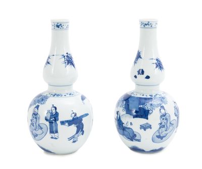 une paire de vases bleus et blancs ornés de personnages sur fond blanc