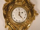 a gold clock on a white wall with a bird on it
