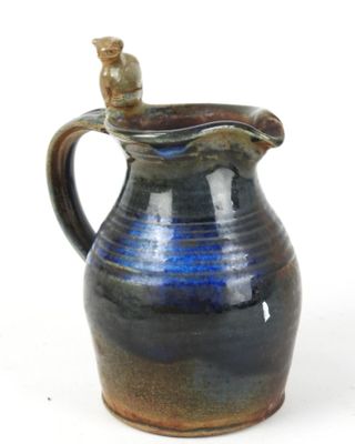 a blue and brown pitcher with a cat on it
