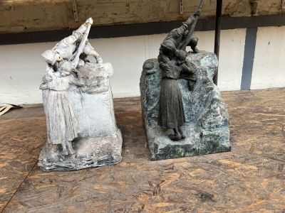 deux statues représentant une femme et un homme assis sur un rocher