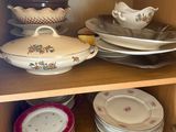 many plates and bowls on a shelf in a cabinet