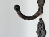 two metal hooks on a wall with a white wall in the background