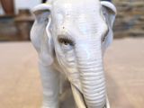 statue of an elephant with tusks standing on a wooden table