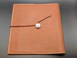 a close up of a brown leather journal with a button on it