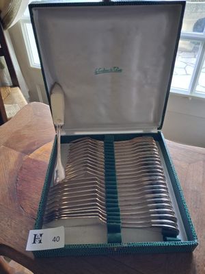 silverware in a case on a wooden table with a window in the background