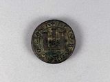 une vieille pièce de monnaie sur laquelle figure une croix, posée sur une surface blanche