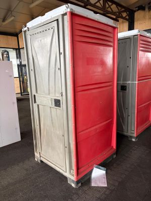 Plusieurs toilettes portables sont alignées dans une zone d'entrepôt