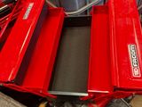 une boîte à outils rouge posée sur une pile d'outils