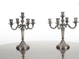 paire de candélabres anciens en métal argenté posés sur une table en verre
