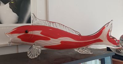 une sculpture représentant un poisson rouge et blanc posée sur une table