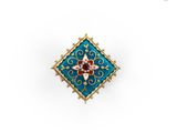a close up of a blue and gold broochle with a red flower