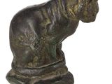 bronze statue of a cat sitting on a rock on a white background