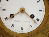 a gold clock with roman numerals on the face