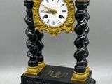 a black and gold clock sitting on top of a table next to a pair of scissors