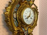 a gold clock on the wall with a bird on it