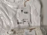 white t - shirt and pants are wrapped in plastic on a table