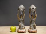 two figurines that are sitting next to a green apple