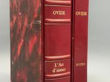 two red books sitting on top of each other on a white surface