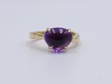 a close up of a purple stone ring on a white surface